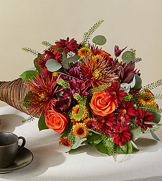 Autumn Herald Cornucopia with orange roses, bronze pompons and red leucadendron