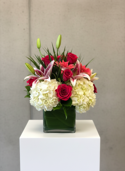 Glamour in Bloom with roses and stargazer lilies in a glass cube vase