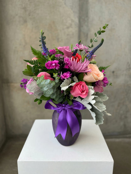 Plum Garden Bouquet with pink and peach roses, purple veronica and red berries in a plum vase